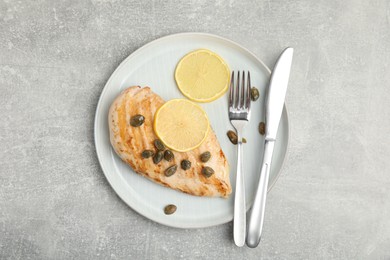 Delicious chicken fillet with capers and lemon served on light grey table, top view