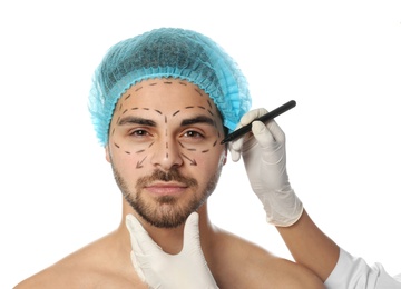 Photo of Doctor drawing marks on man's face for cosmetic surgery operation against white background