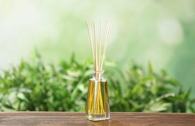 Reed air freshener on wooden table against blurred green background