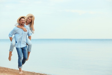 Happy romantic couple walking on beach, space for text