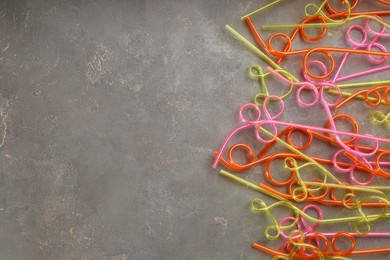 Colorful plastic drinking straws on grey stone table, flat lay. Space for text