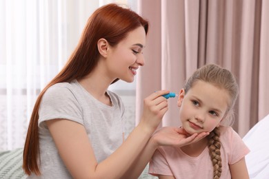 Mother dripping medication into daughter's ear at home