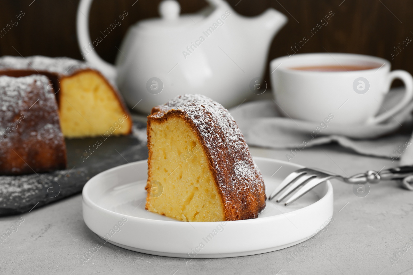 Photo of Piece of homemade yogurt cake with powdered sugar on light grey table