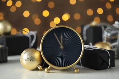 Photo of Stylish clock with Christmas decor on white table, closeup. New Year countdown