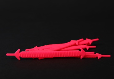 Pink silicone shoe laces on black background. Space for text