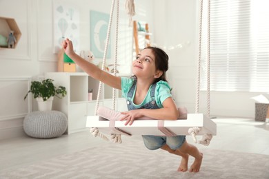 Photo of Cute little girl playing on swing at home