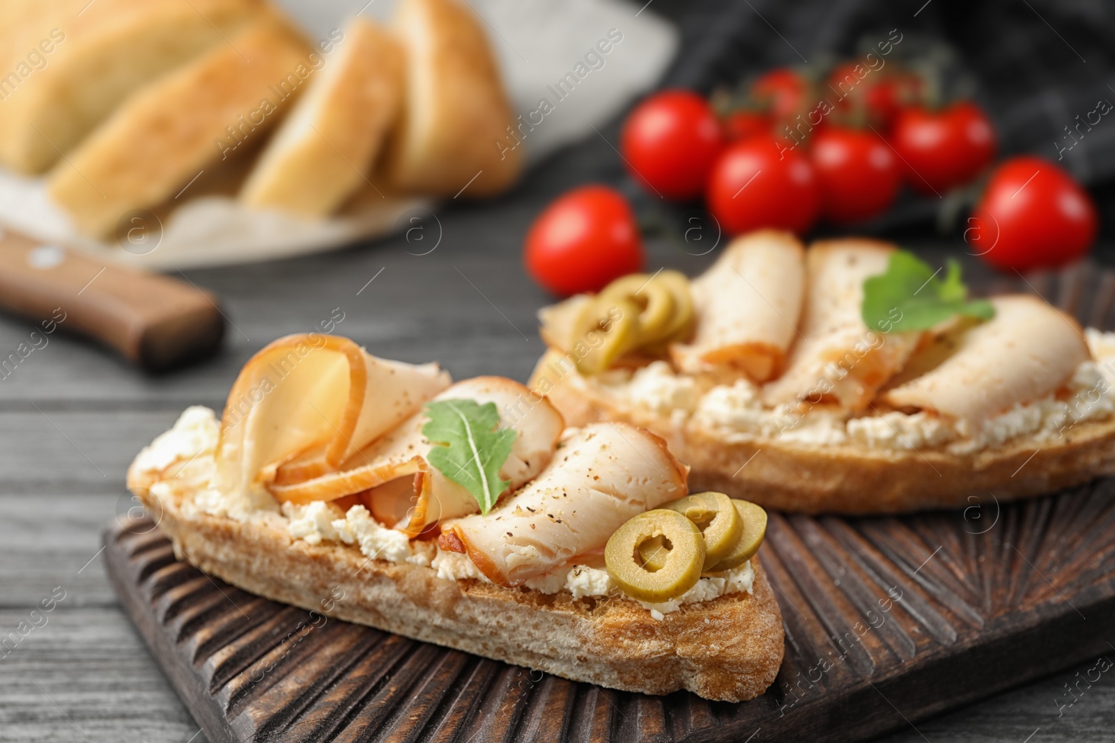 Photo of Board with delicious chicken bruschettas on table, closeup