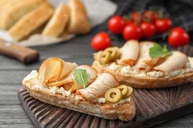 Photo of Board with delicious chicken bruschettas on table, closeup