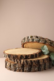 Photo of Presentation for product. Wooden stumps and eucalyptus branches on beige background. Space for text