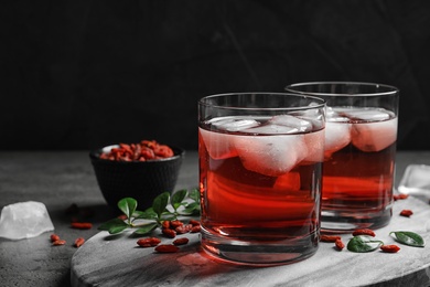 Photo of Healthy goji juice with ice in glasses on table