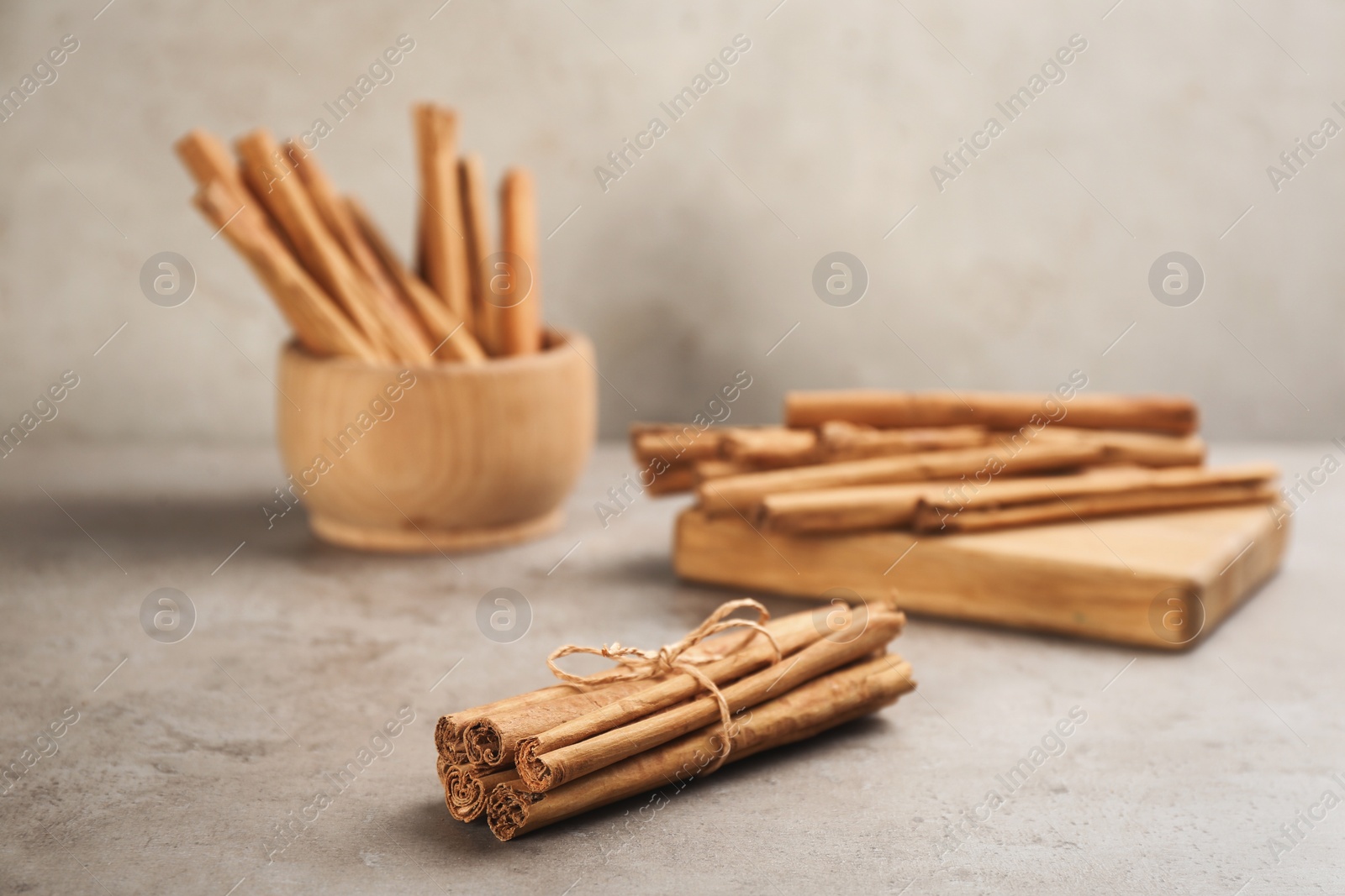 Photo of Aromatic cinnamon sticks on grey stone table