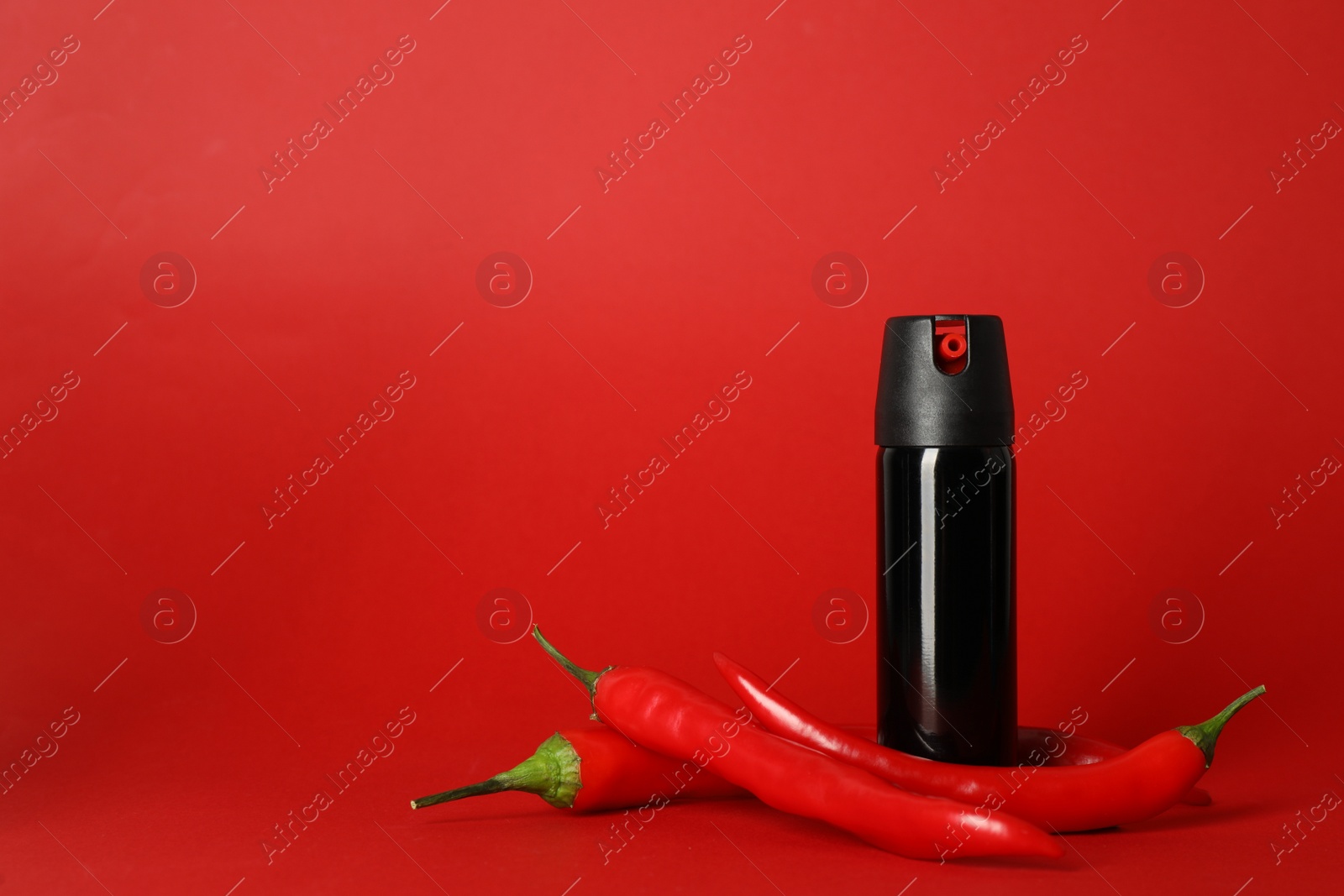 Photo of Bottle of gas pepper spray and fresh chili peppers on red background. Space for text