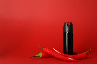 Photo of Bottle of gas pepper spray and fresh chili peppers on red background. Space for text