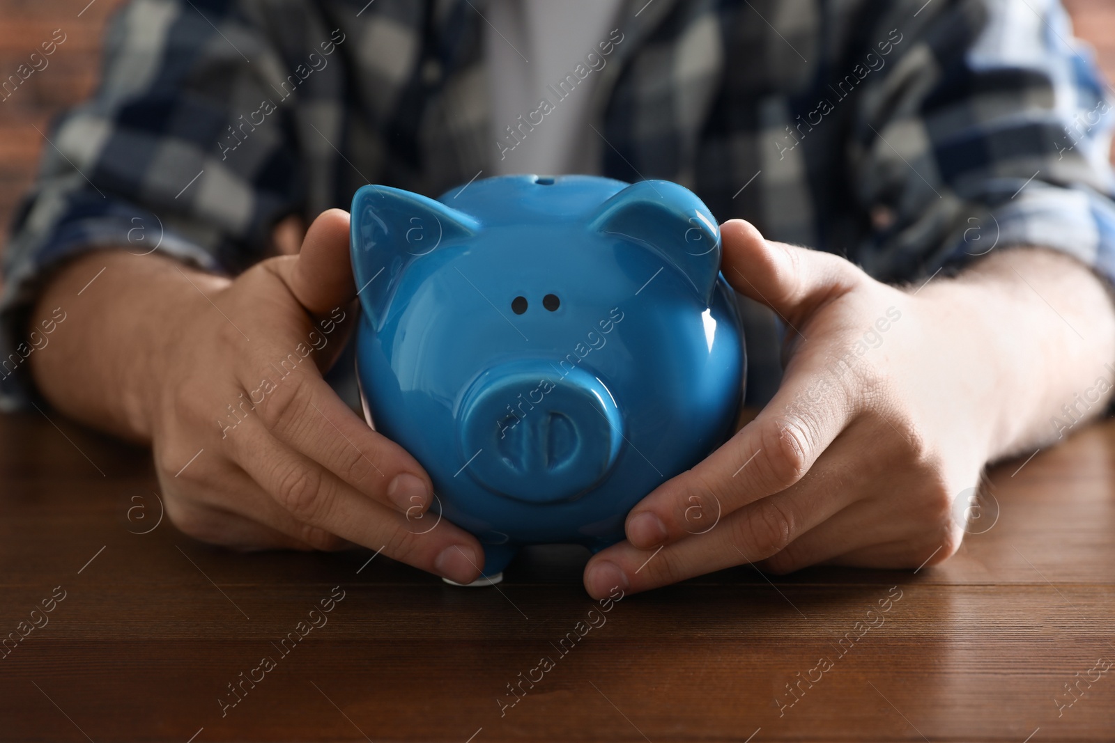 Photo of Man with piggy bank at wooden table, closeup