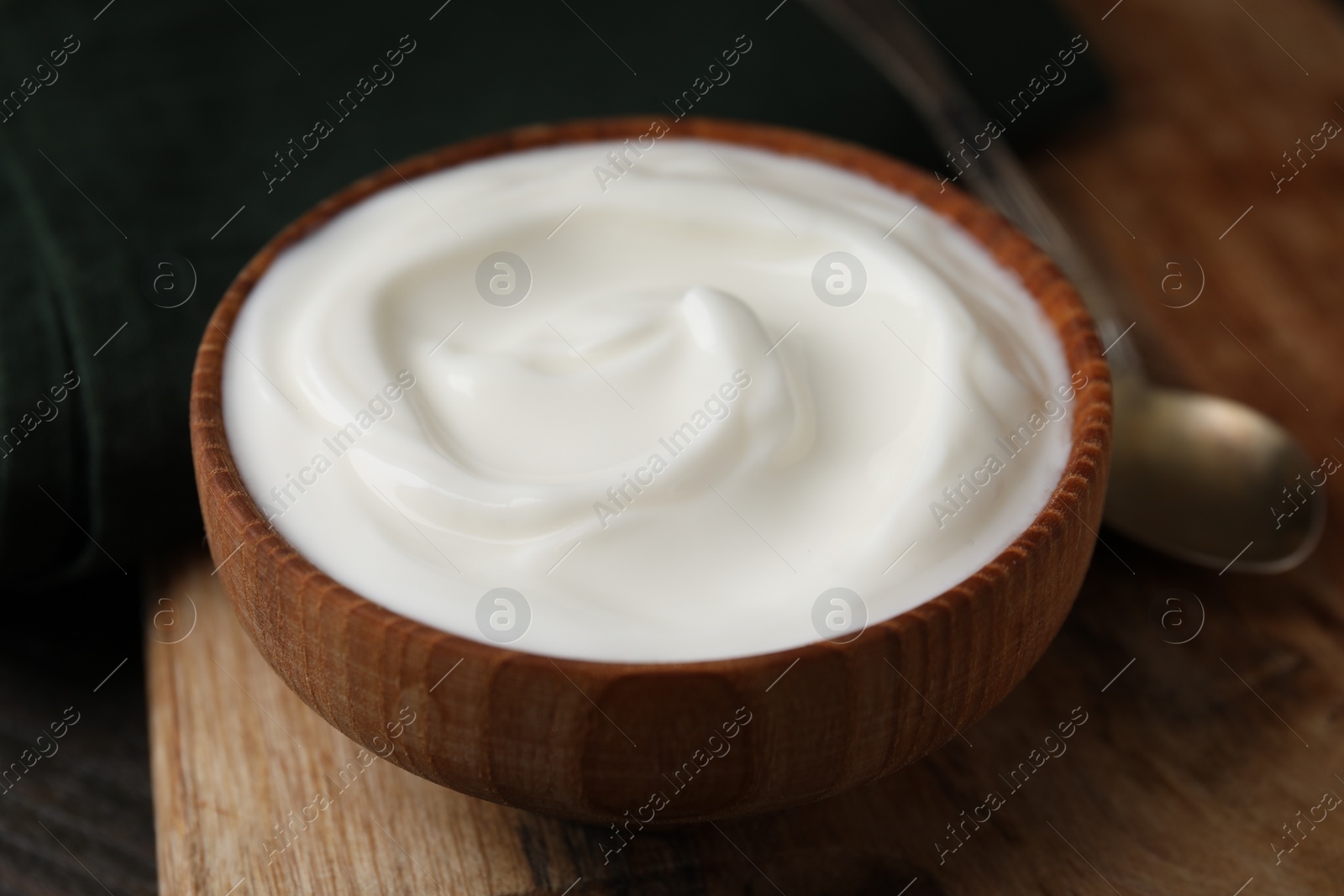 Photo of Delicious natural yogurt in bowl and spoon on table, closeup