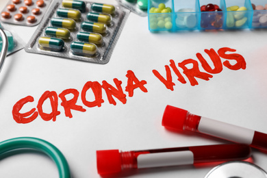 Photo of Phrase CORONA VIRUS and medicines on white background