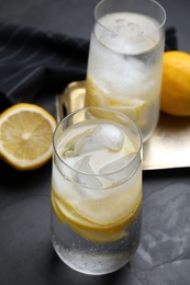 Photo of Soda water with lemon slices and ice cubes on grey table