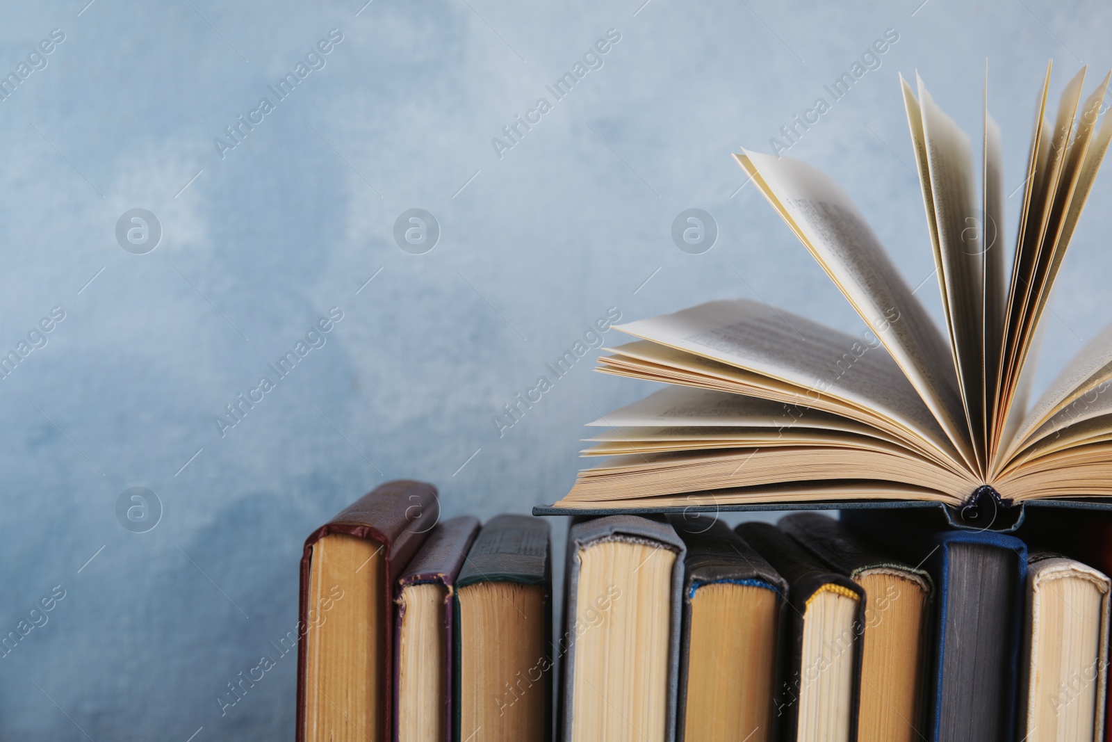 Photo of Stack of hardcover books on light blue background. Space for text