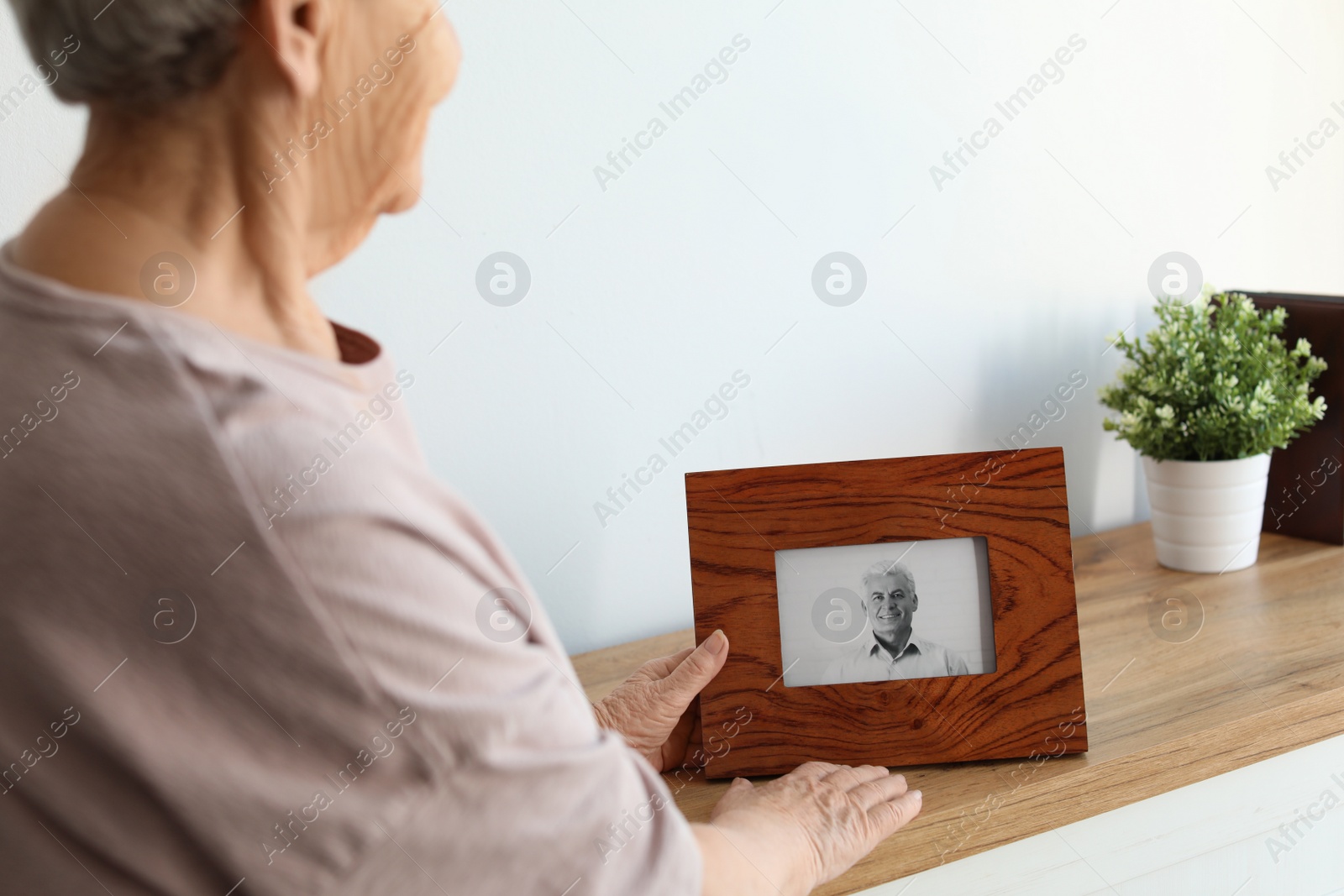 Photo of Elderly woman with framed photo of her son at home