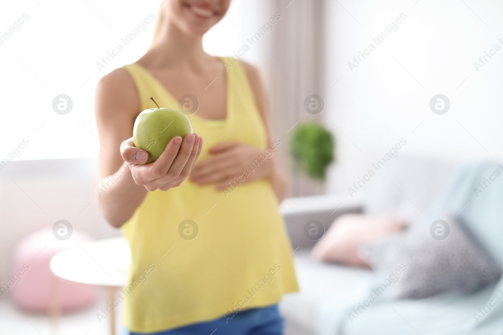 Photo of Young pregnant woman holding apple at home