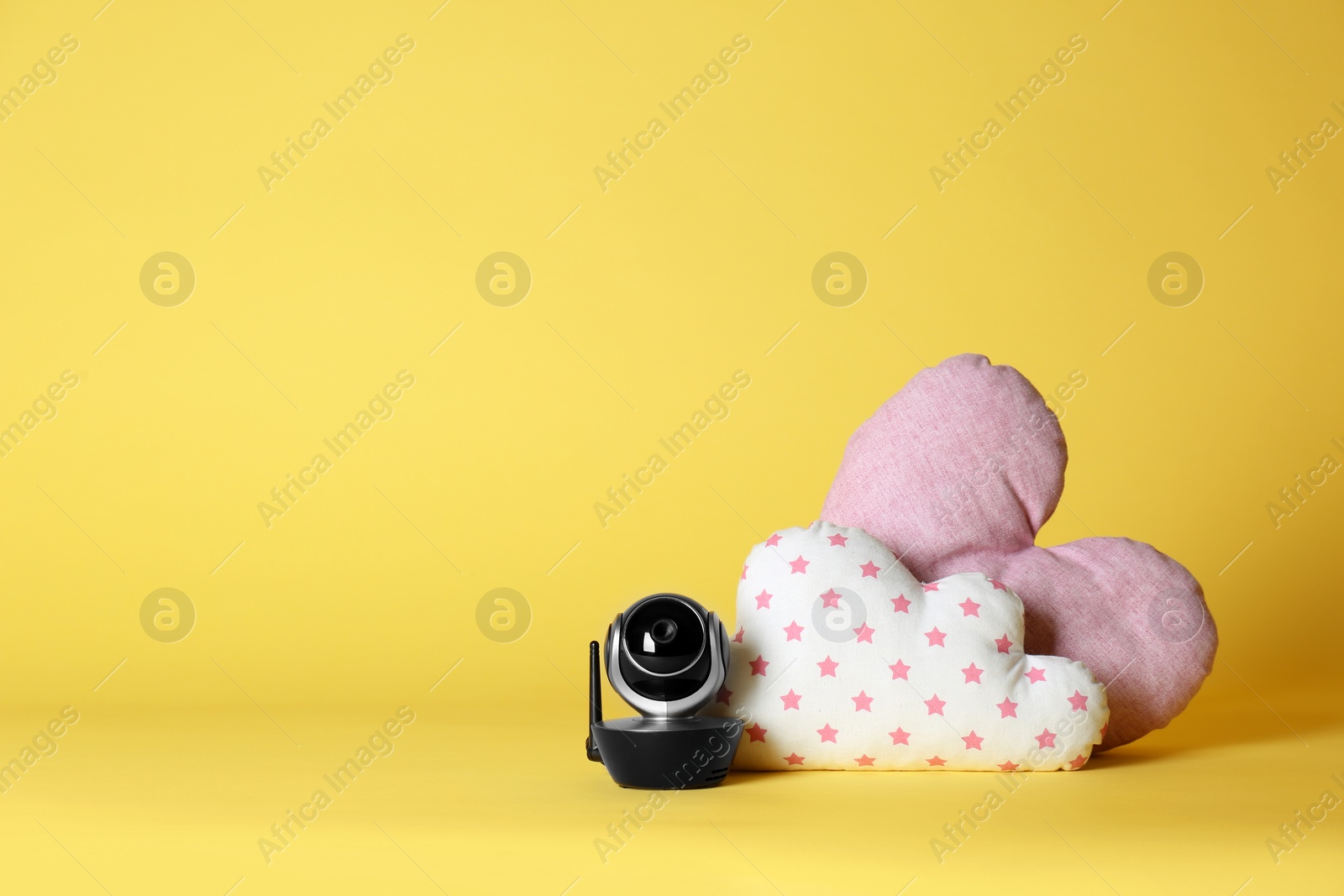 Photo of Modern CCTV security camera and decorative nursery pillows on color background. Space for text
