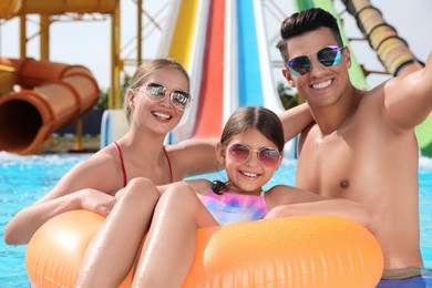 Photo of Happy family taking selfie in swimming pool at water park