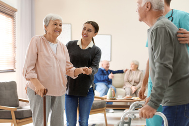 Photo of Care workers helping to elderly patients to walk in geriatric hospice