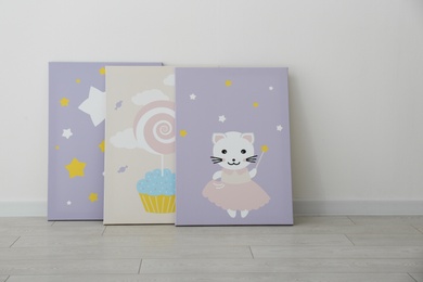 Photo of Different cute pictures on floor near white wall. Children's room interior elements