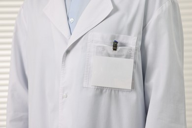 Doctor with empty badge in hospital, closeup