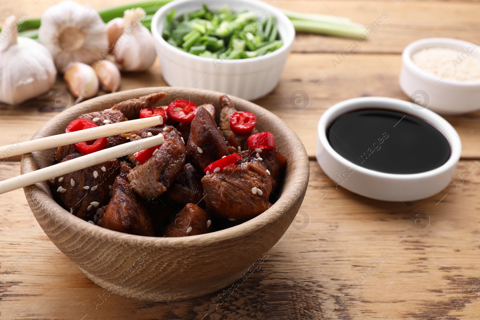 Photo of Tasty roasted meat served with soy sauce on wooden table, closeup. Space for text
