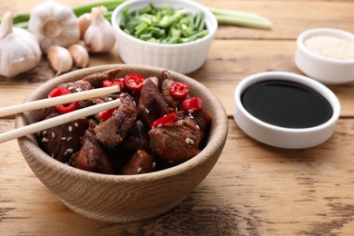 Tasty roasted meat served with soy sauce on wooden table, closeup. Space for text