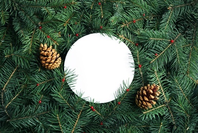 Blank card and pine cones on Christmas tree branches as background, flat lay. Space for text