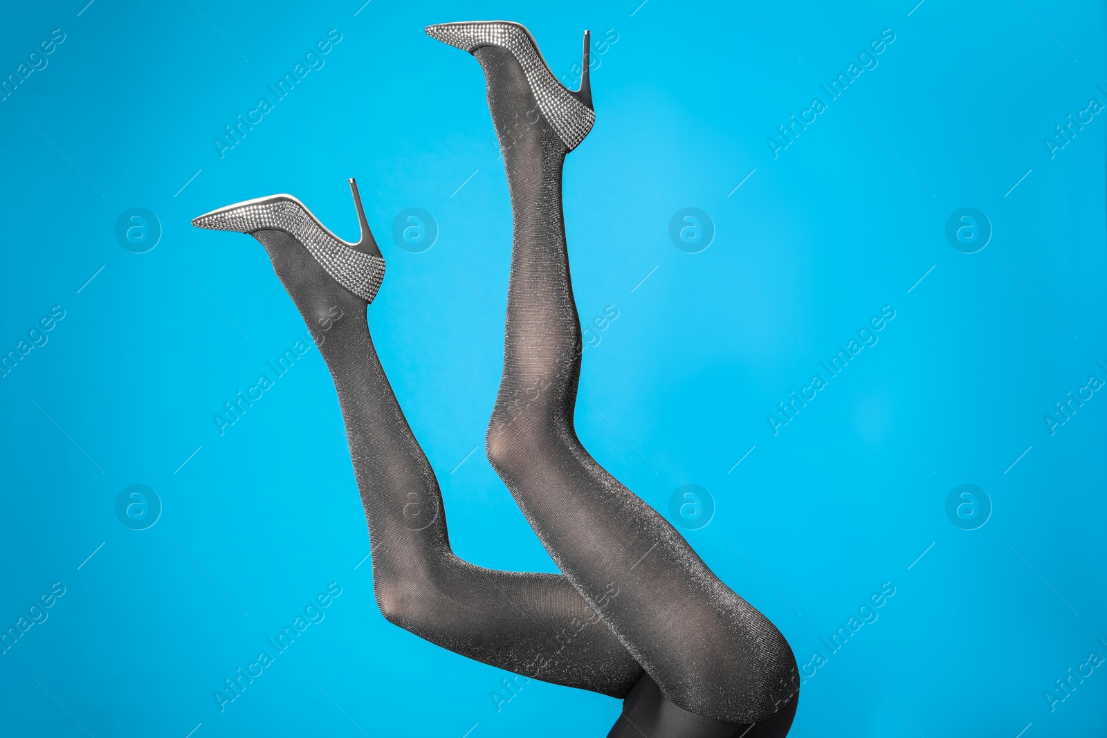 Photo of Woman wearing black tights and stylish shoes on blue background, closeup of legs