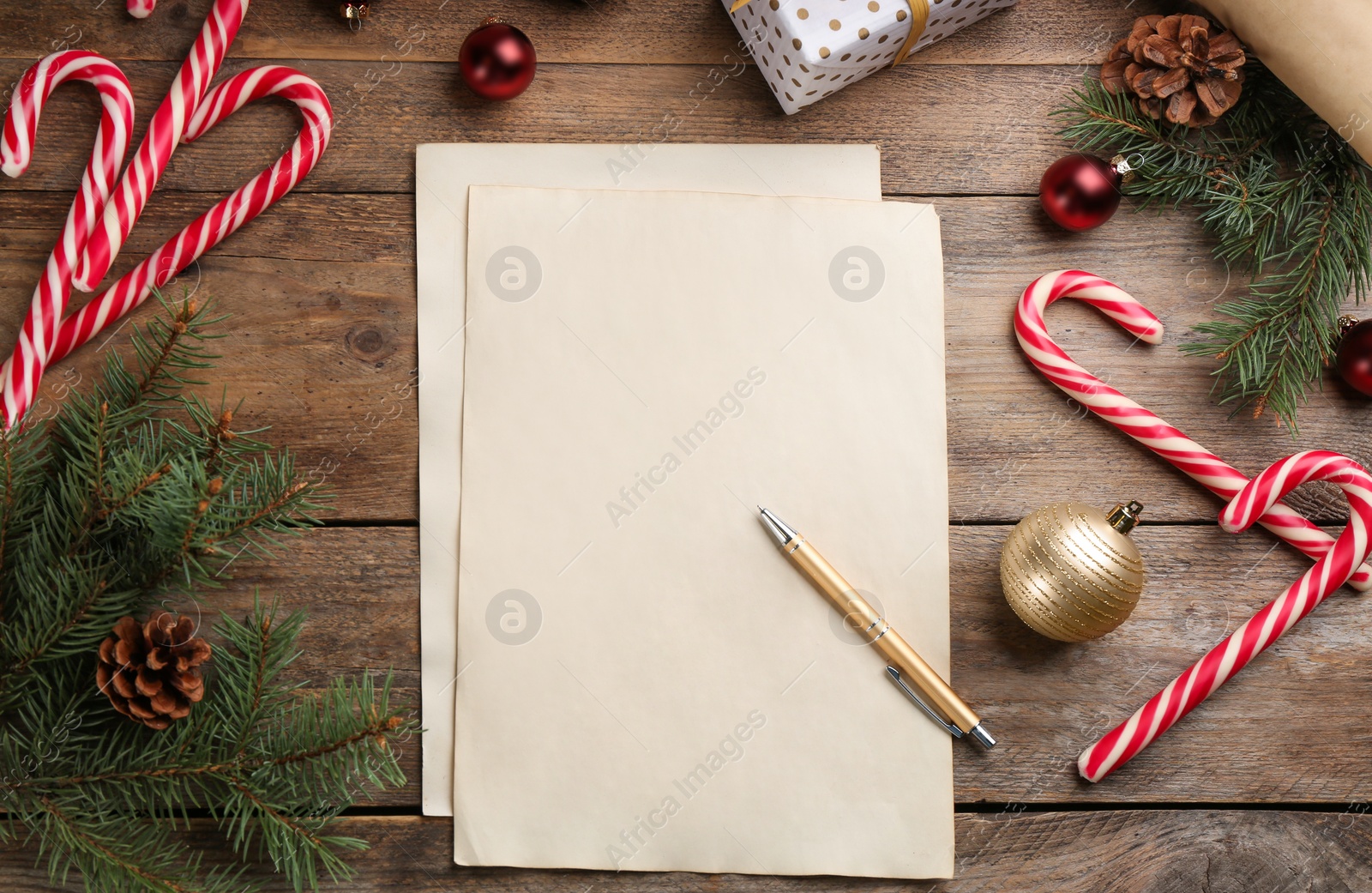 Photo of Flat lay composition with paper and Christmas decor on wooden table. Writing letter to Santa Claus