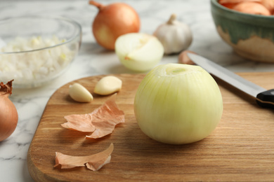 Photo of Peeled onion bulb and knife on wooden board