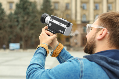 Photo of Young man with vintage video camera on city street, closeup