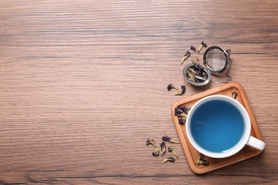Photo of Organic blue Anchan in cup on wooden table, flat lay with space for text. Herbal tea