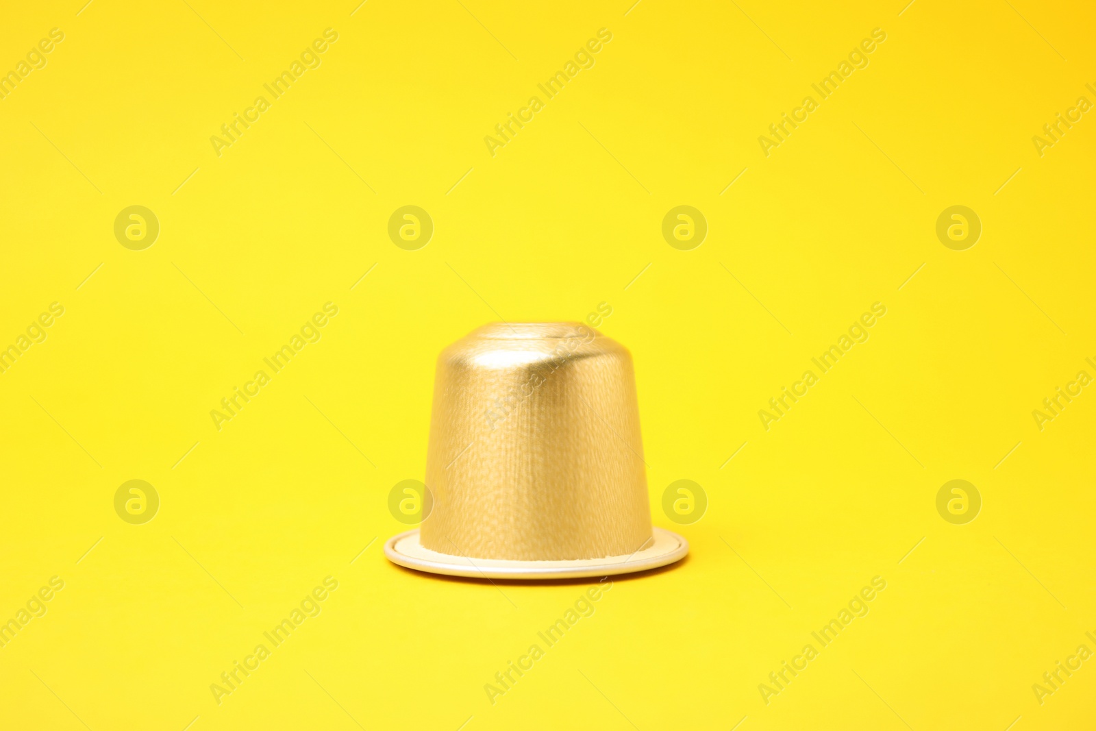 Photo of One plastic coffee capsule on yellow background