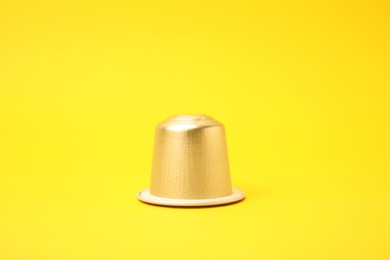 Photo of One plastic coffee capsule on yellow background