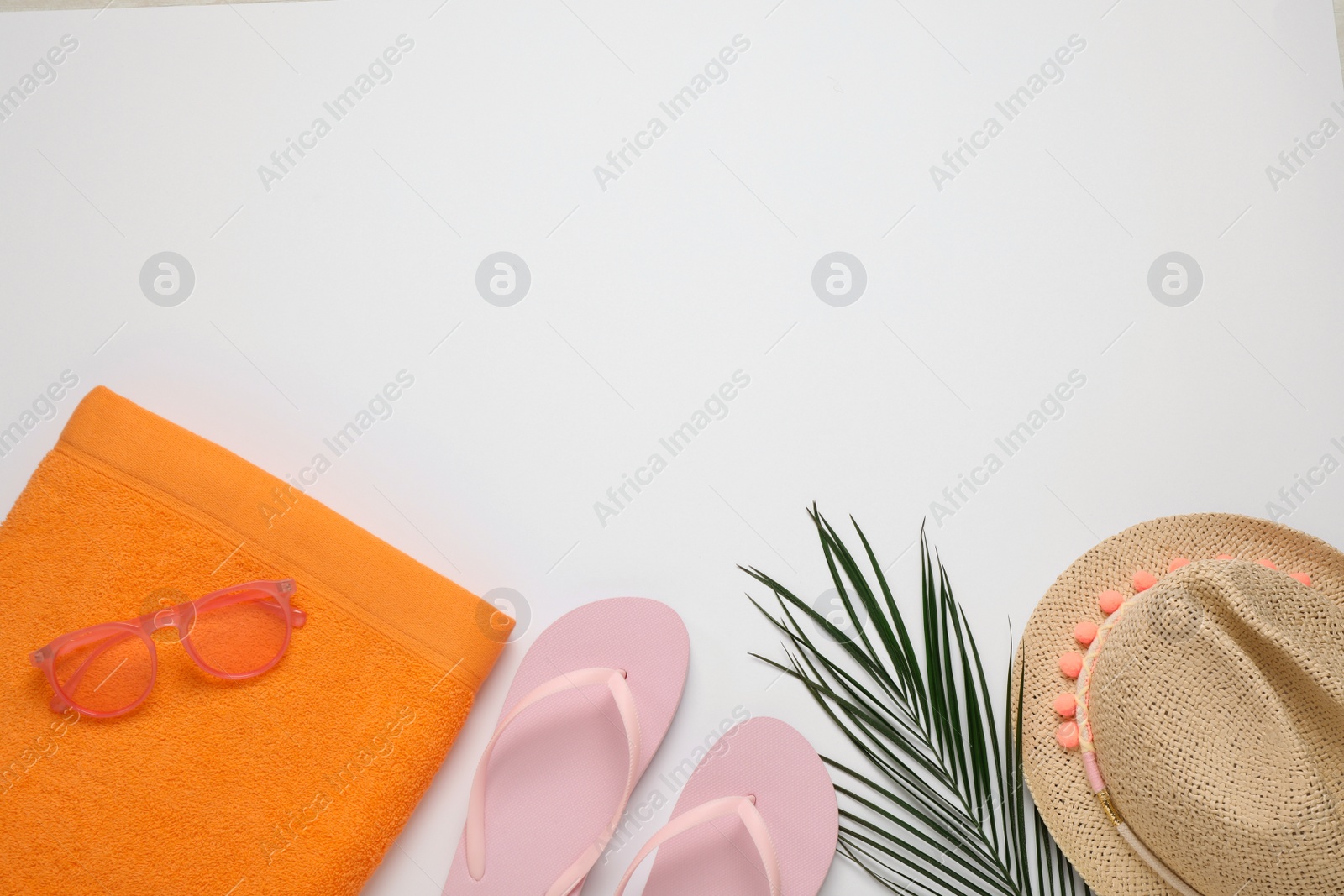 Photo of Beach towel, flip flops , sunglasses and hat on white background, flat lay. Space for text
