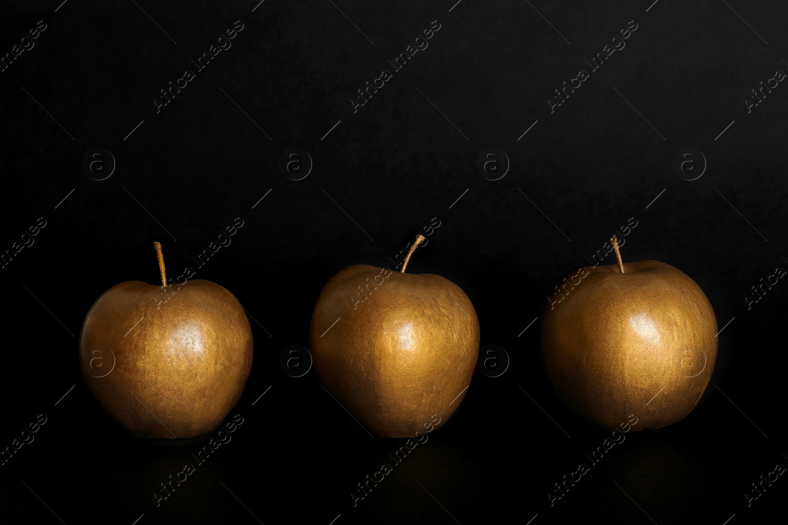 Photo of Gold painted fresh apples on black background