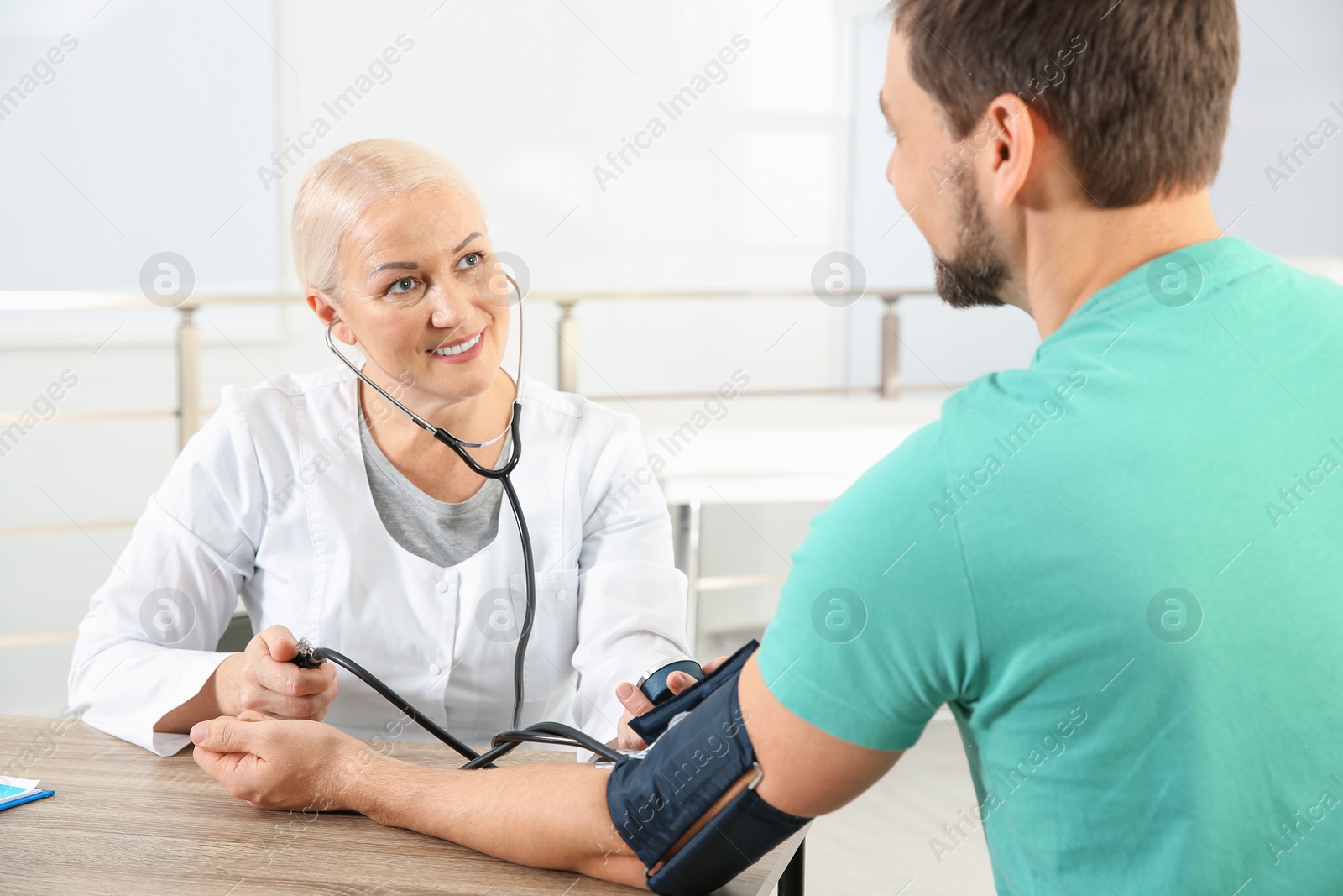 Photo of Man visiting doctor in hospital. Measuring blood pressure and checking pulse