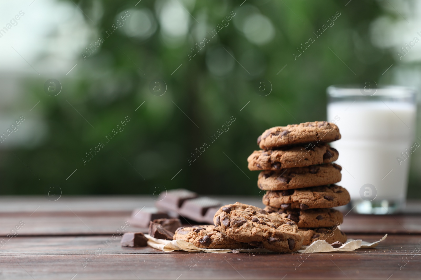 Photo of Delicious chocolate chip cookies on wooden table, space for text