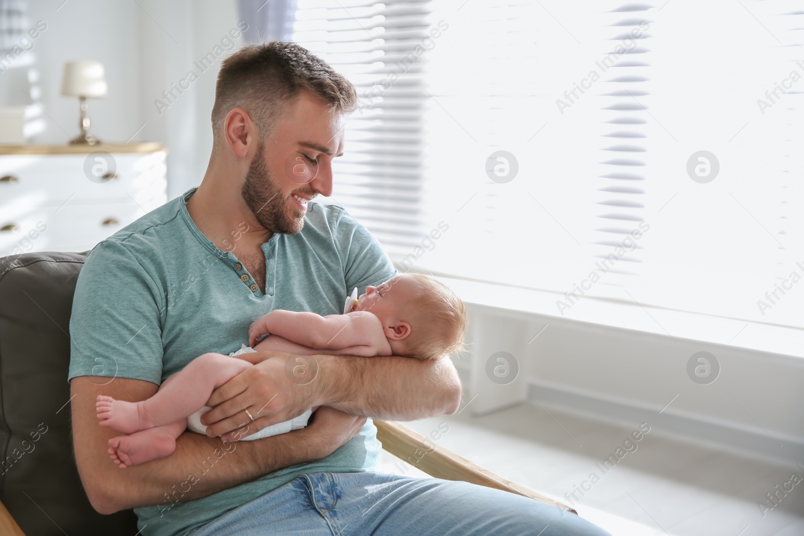 Photo of Father with his newborn son at home. Space for text