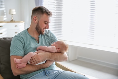 Father with his newborn son at home. Space for text