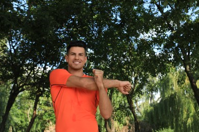 Photo of Handsome man in sportswear doing exercises outdoors on sunny day