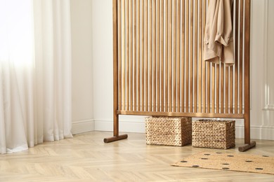 Photo of Stylish room with folding screen and storage baskets. Interior design