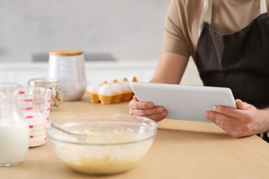 Man making dough while watching online cooking course via tablet in kitchen, closeup