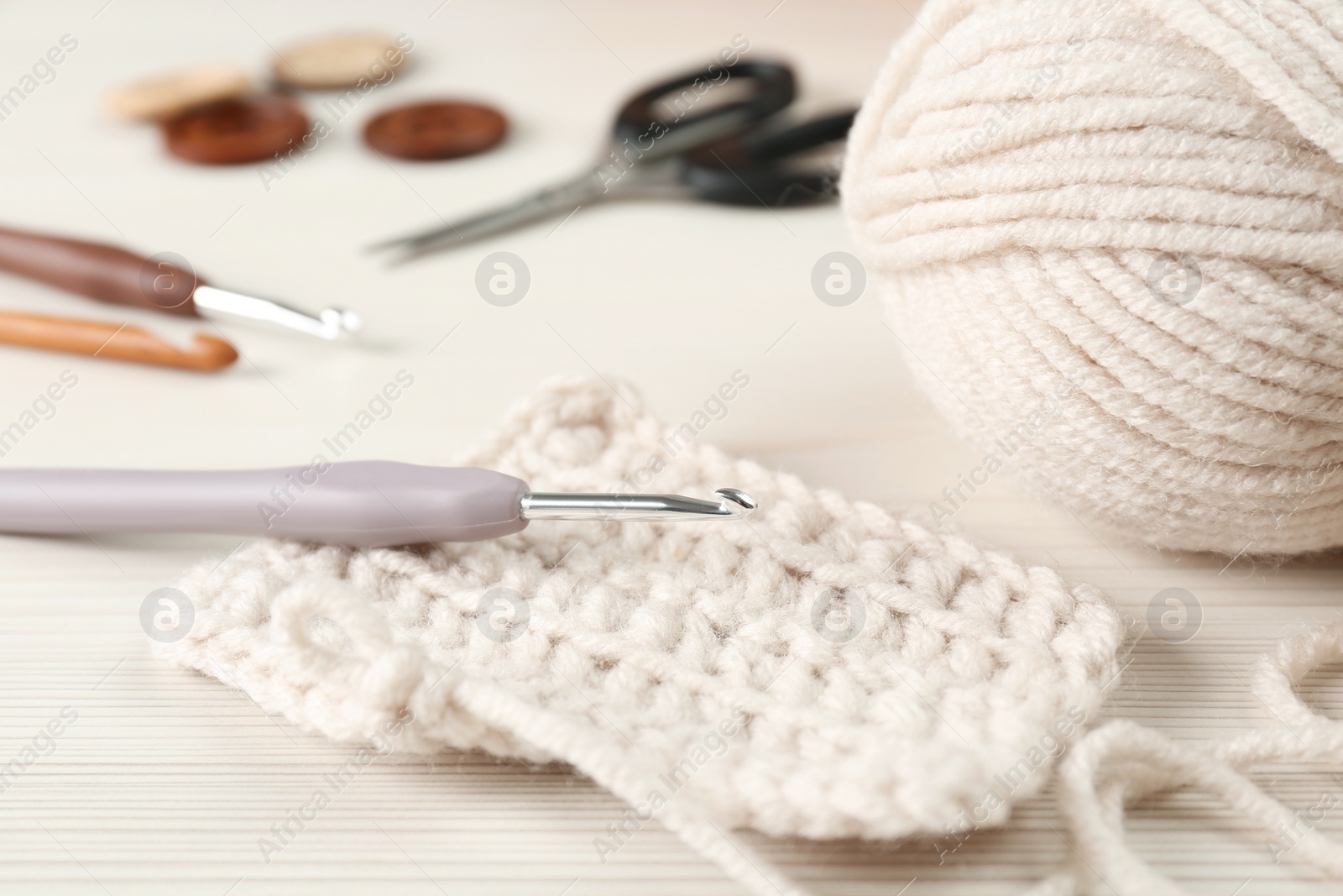 Photo of Knitting and crochet hook on wooden table, closeup