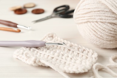 Knitting and crochet hook on wooden table, closeup